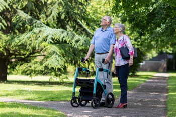 Man with rollator walking in the park with his wife