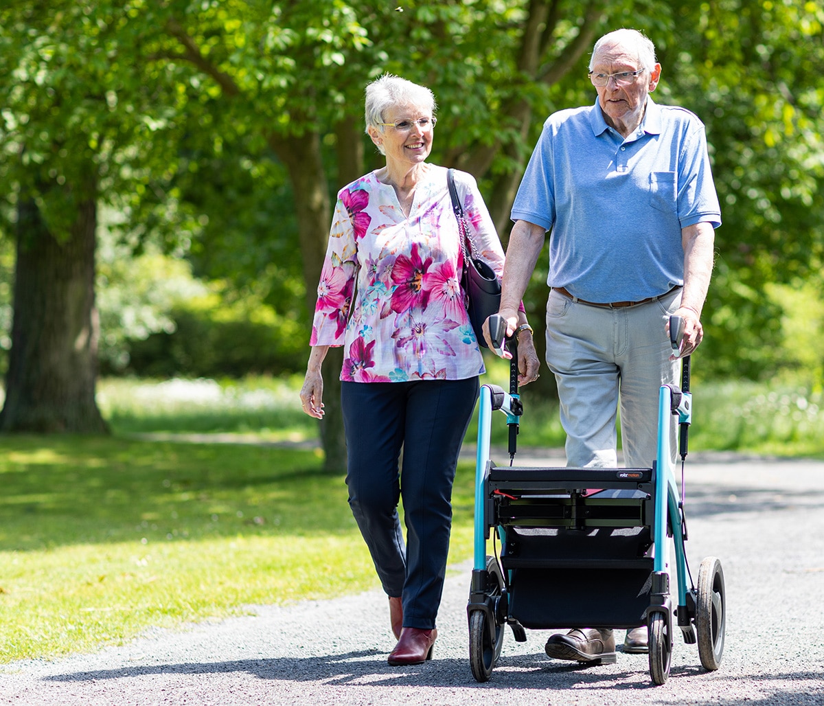 Man loopt met een blauwe Rollz Motion rollator en rolstoel in het park