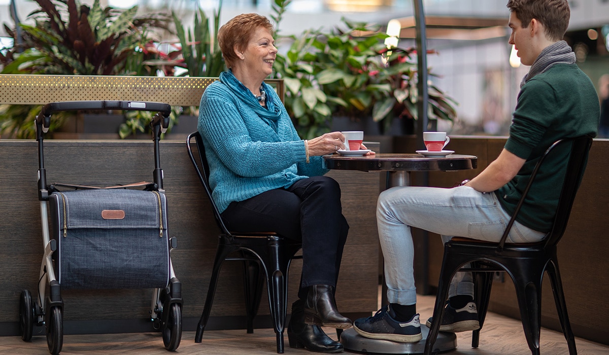 Femme buvant un café avec son fils après avoir marché dans le centre commercial avec un rollator Rollz Flex