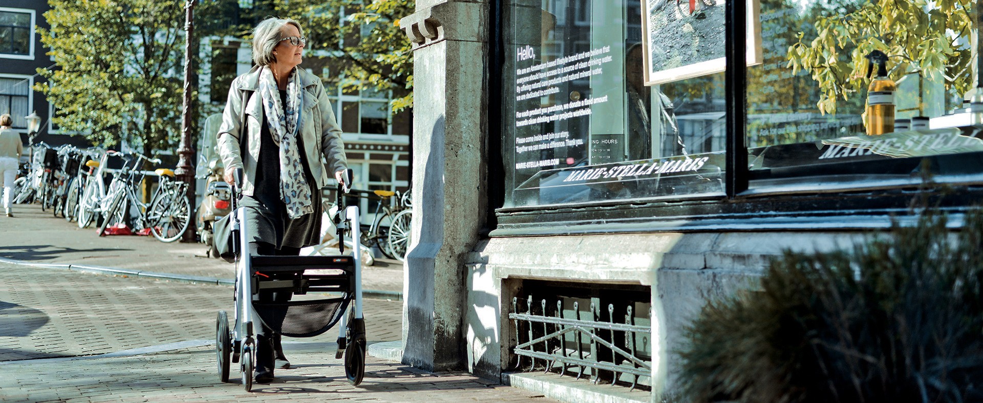 Dame loopt met een rollator in Amsterdam en kijkt naar een etalage.