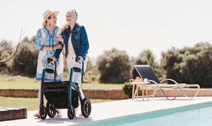 Frau geht mit einem Rollz Motion Performance Rollator in der Nähe eines Schwimmbads