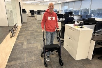 Mann, der einen Rollz Motion Rollator benutzt, um seine Behinderung bei der Arbeit auszugleichen