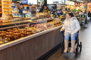 Femme conduisant un fauteuil roulant électrique Rollz Motion dans un marché
