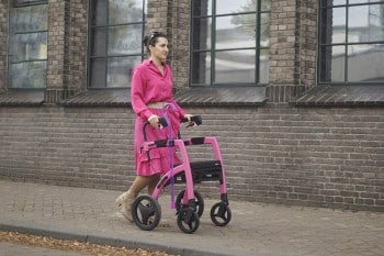 Girl walking with a pink rollator while having mobility issues